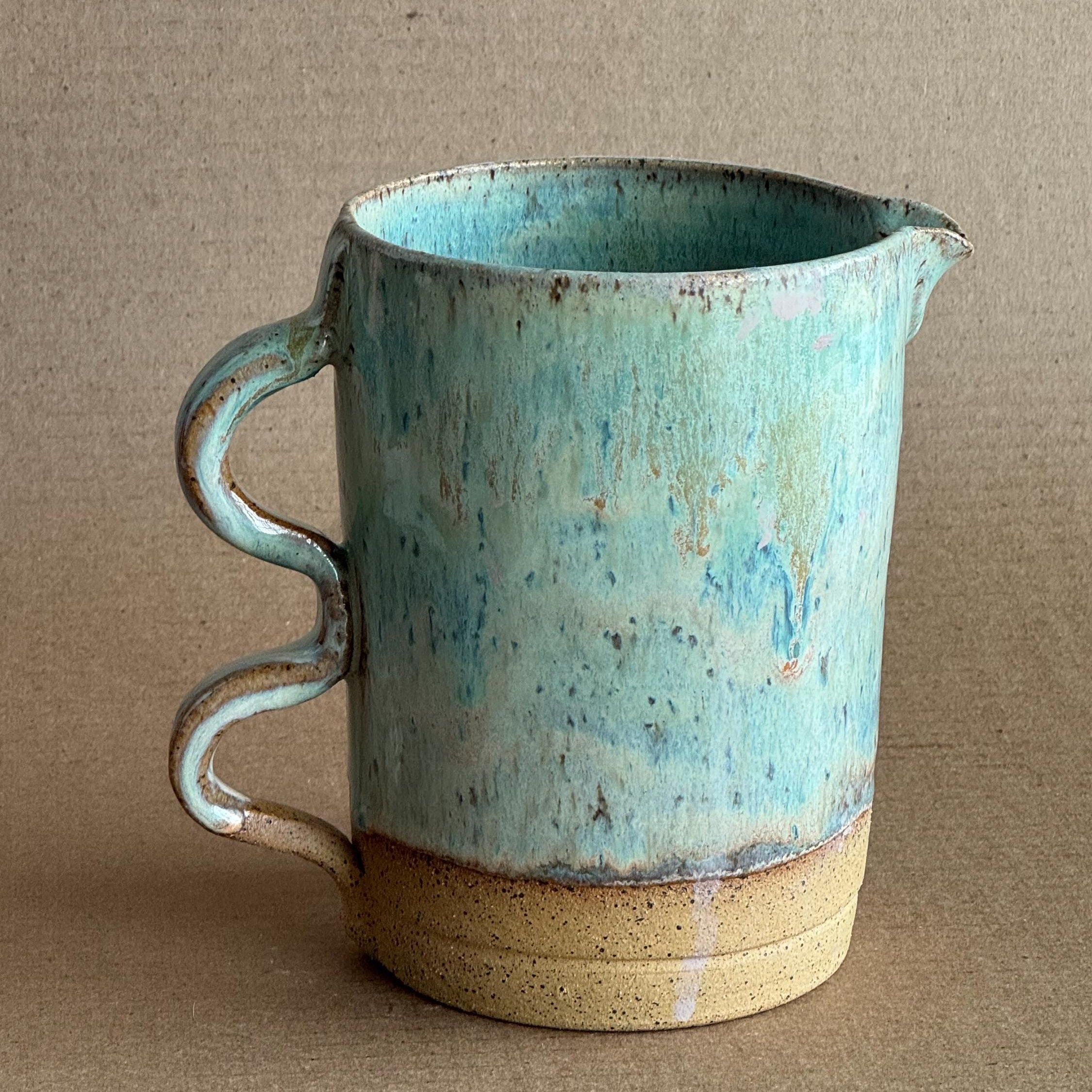 Ceramic pitcher with a blue and beige design on a brown background