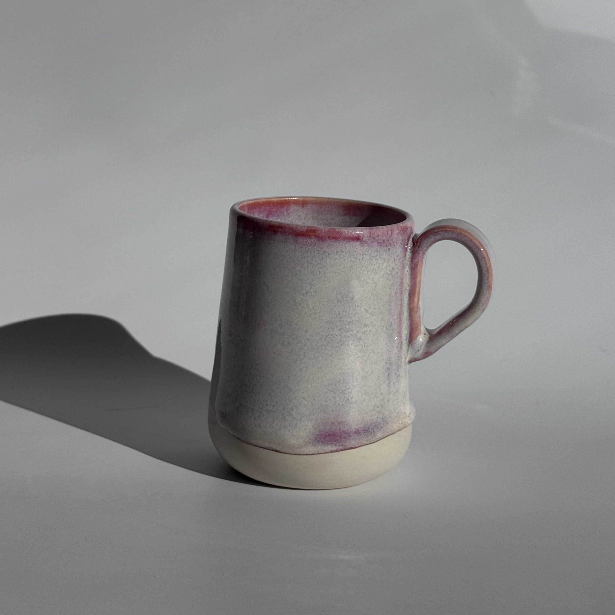 Ceramic mug with a purple rim and base on a gray background