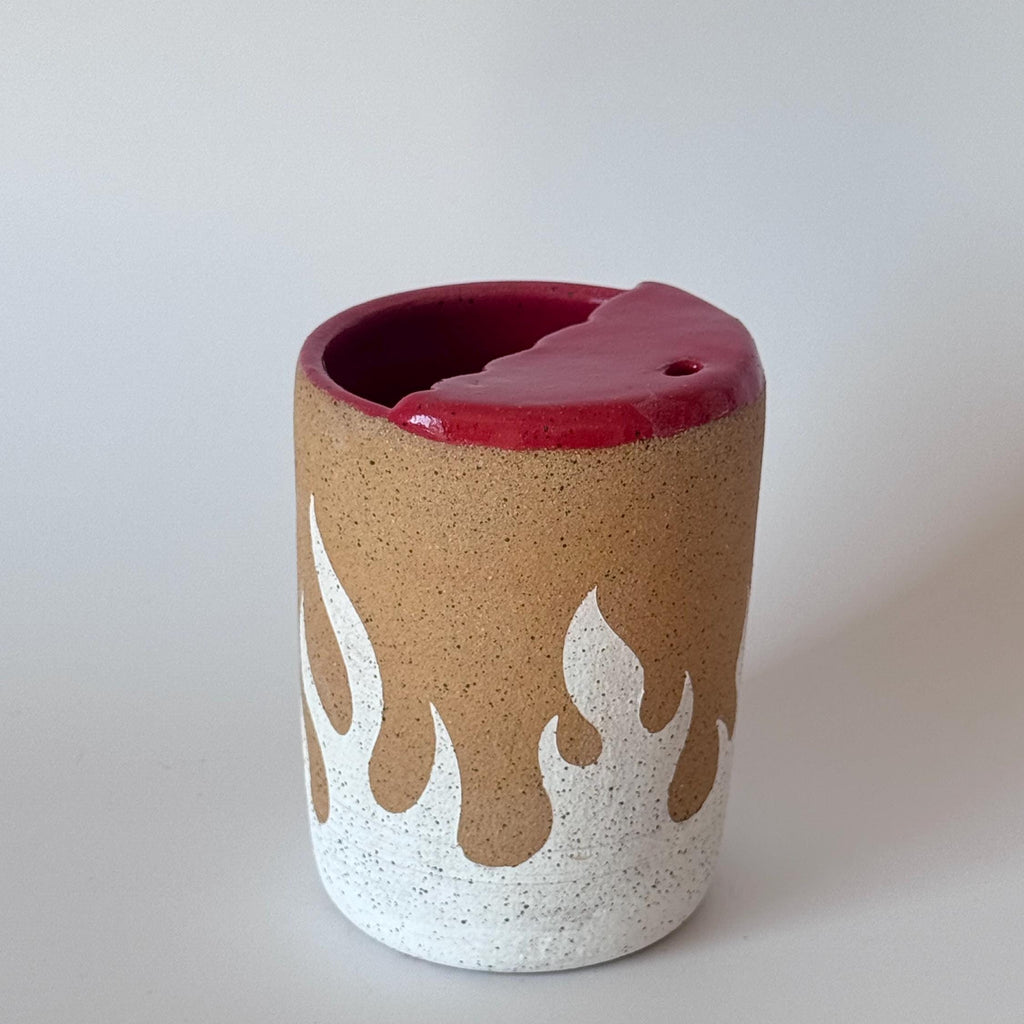 Ceramic cup with flame design and red interior on a white background
